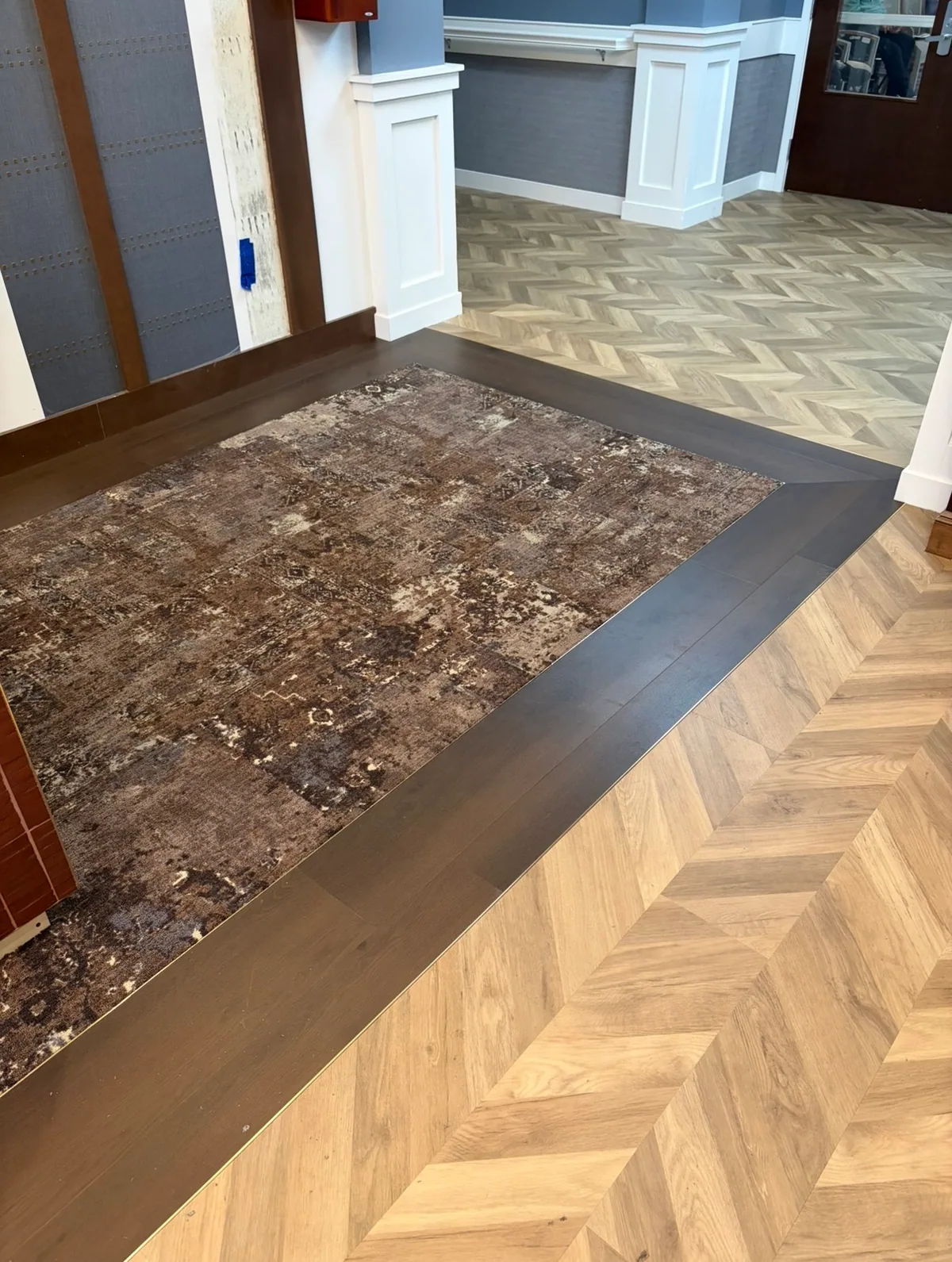 Patterned entry flooring with a dark border around an inset mat