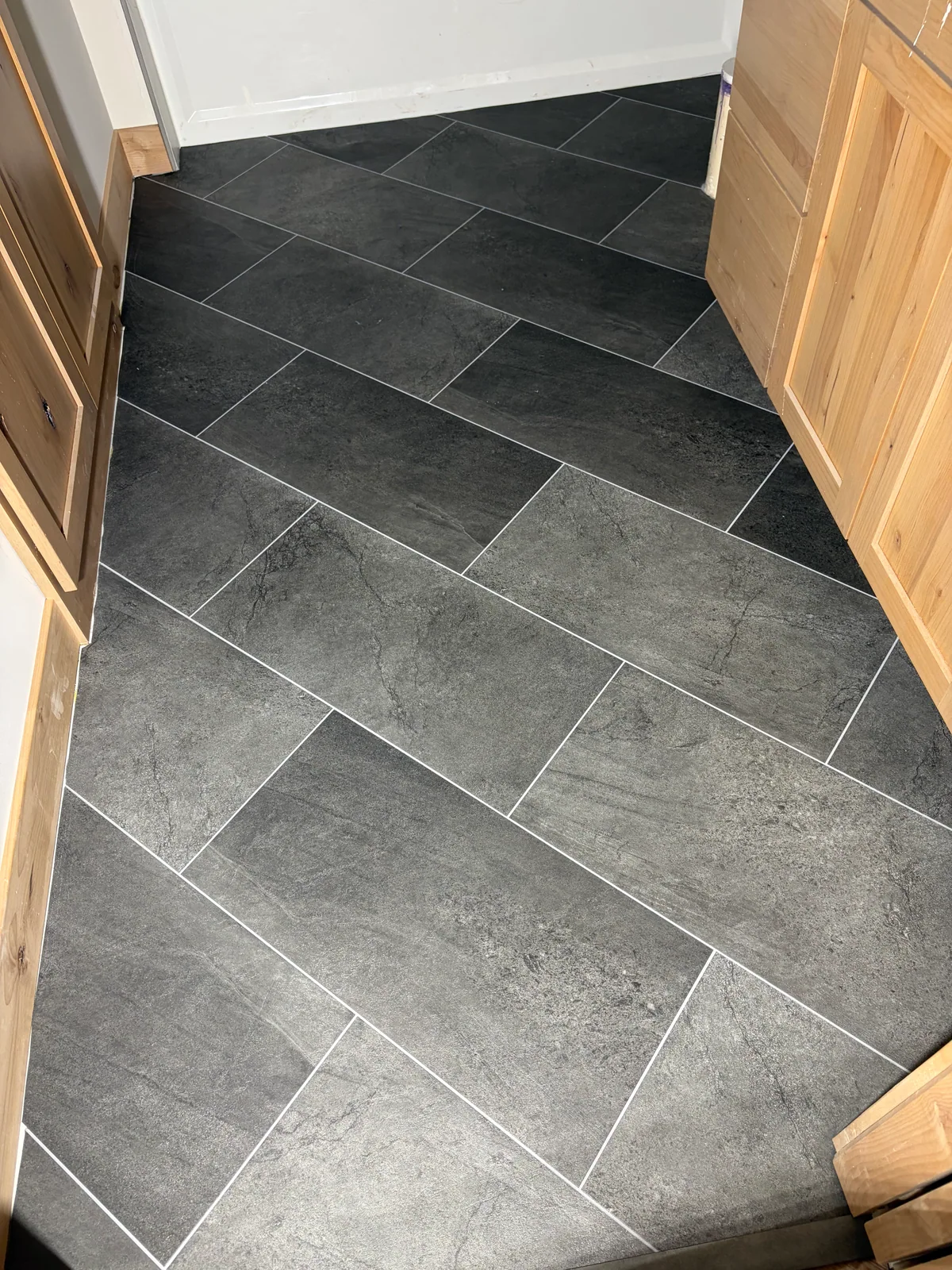 Dark rectangular floor tile laid in an offset pattern