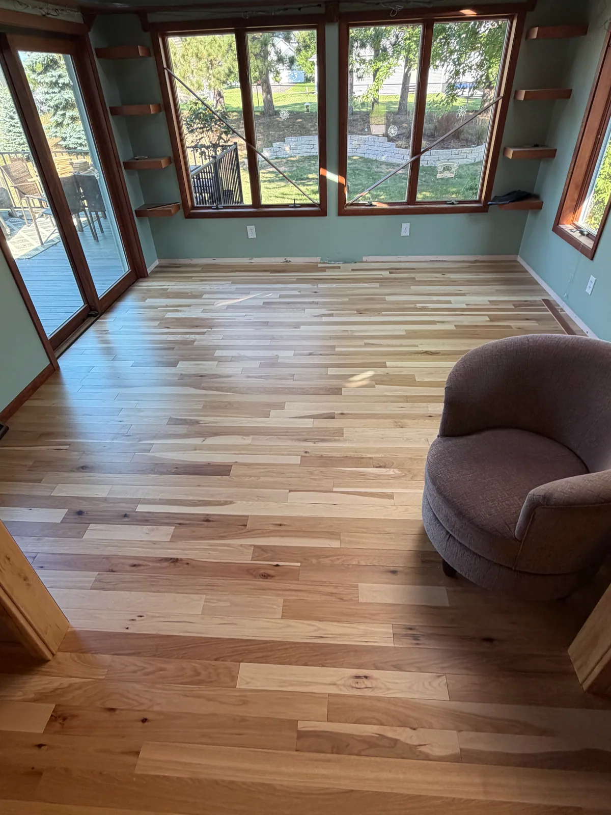 Varied-tone wood flooring in a sunroom with windows on three sides